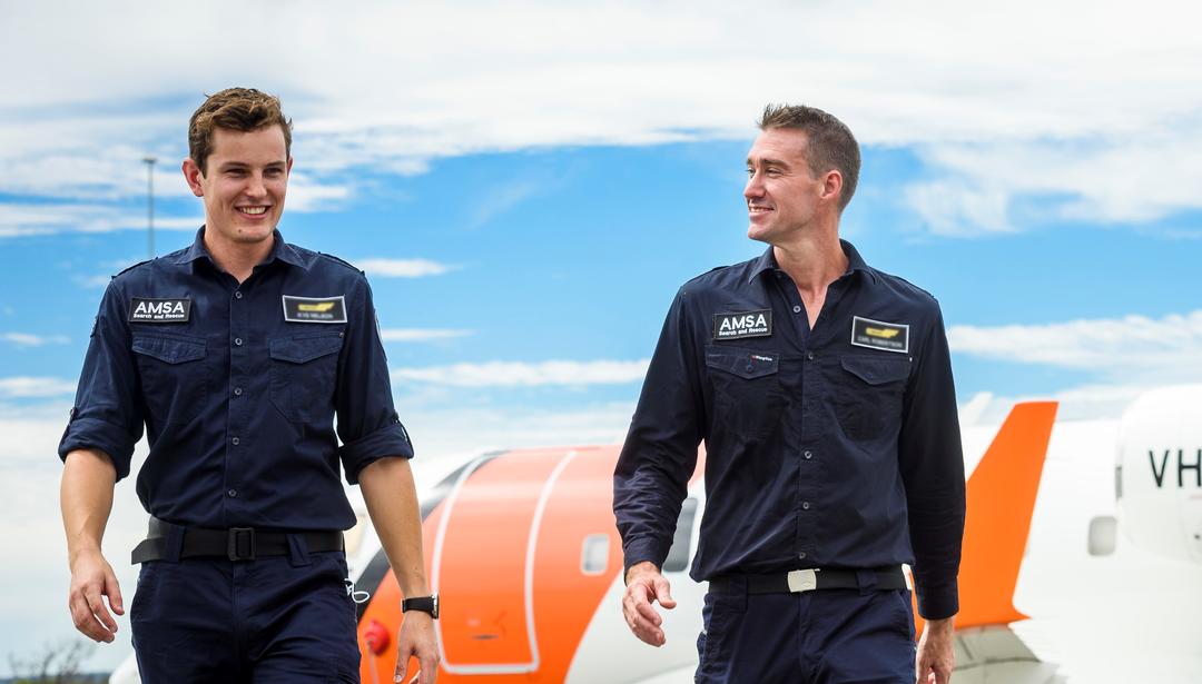 Two men walking in front of planes