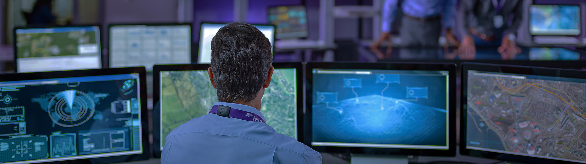 Back of man working on multiple monitors