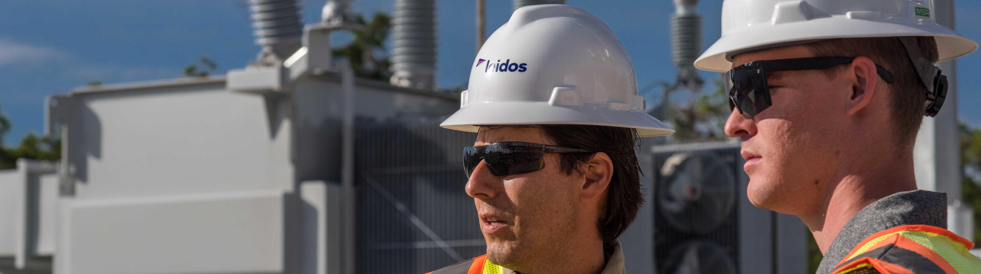 Leidos engineers with hard hats and safety vests at a substation