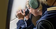 Woman using binoculars to look at of window