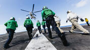 Sailors assigned to supply department runs towards cargo on the flight deck of Nimitz-class aircraft carrier USS George Washington (CVN 73) after it was dropped off by an AS-332 Super Puma helicopter