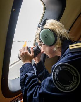 Woman looking out of a plane for research and rescue mission