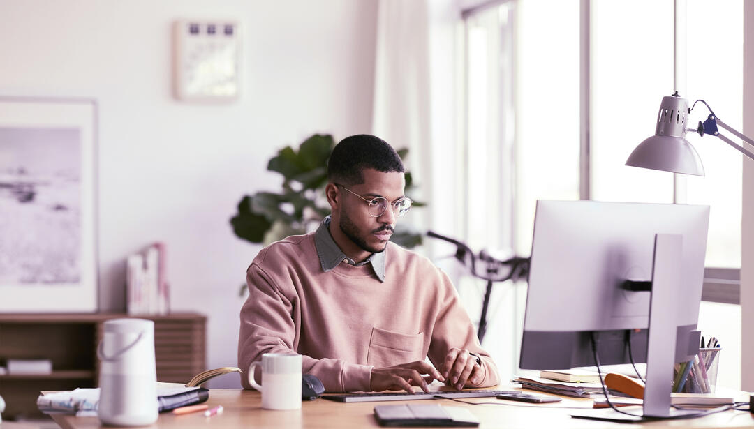 man working on a computer at a desk in a brightly lit office