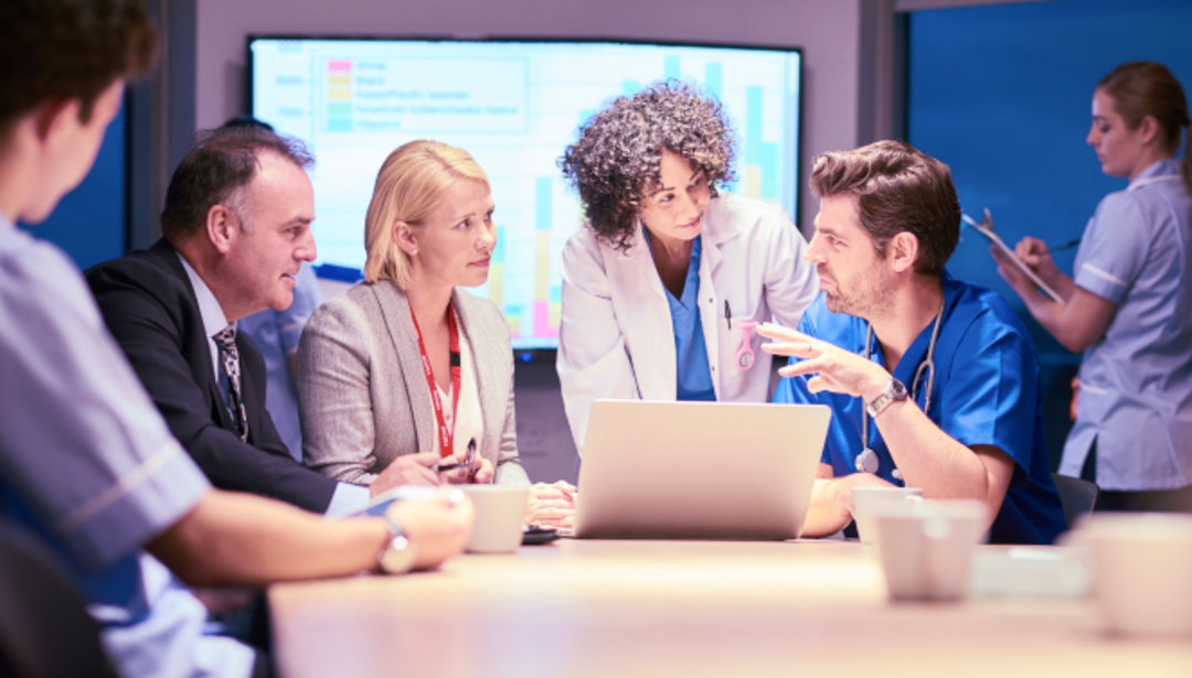 Medical professionals having a conversation around a laptop