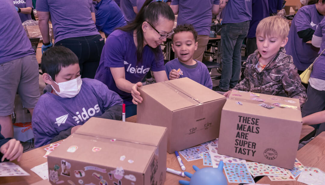 Children packaging meals for generosity feeds community event