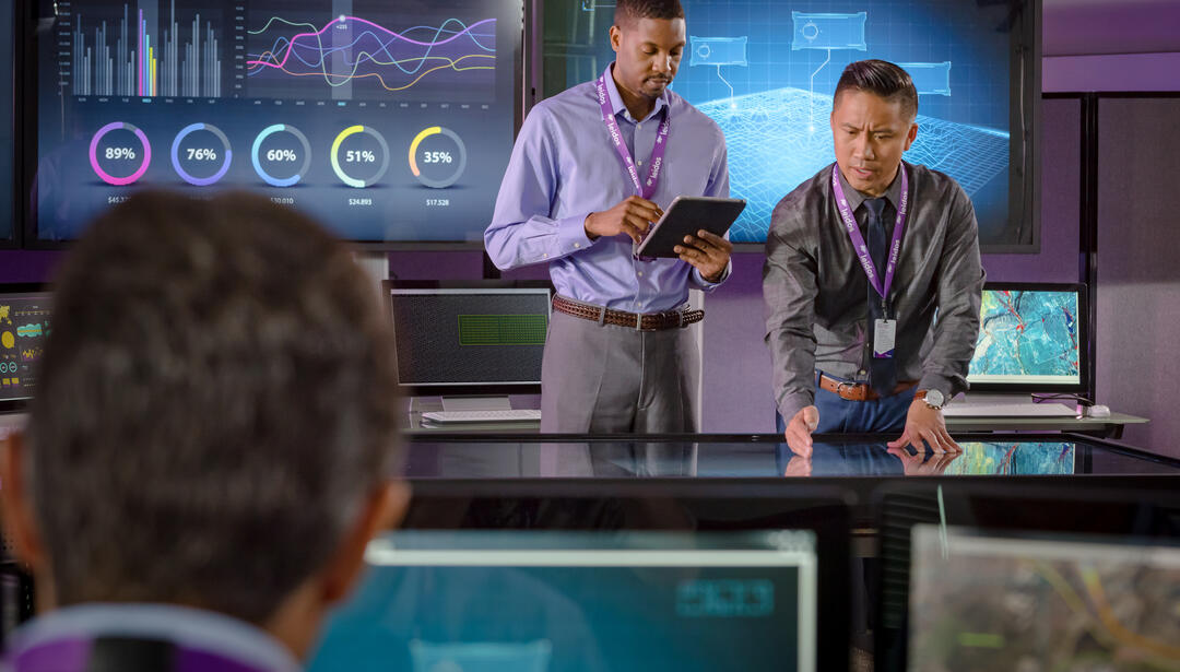 men in front of an interactive talbe with interactive screens behind