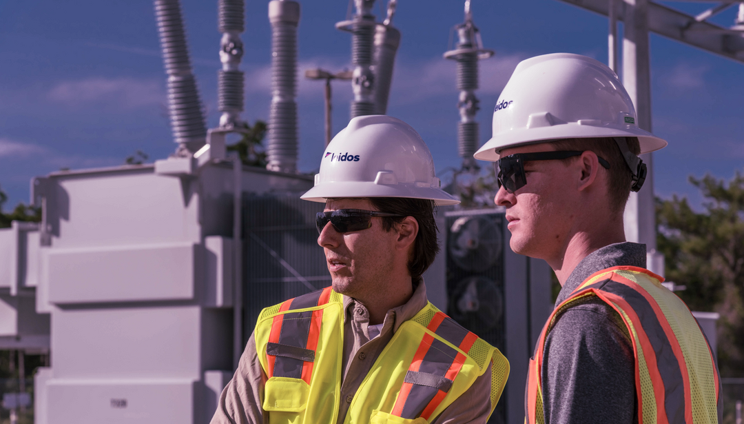 Leidos engineers with hard hats and safety vests at a substation