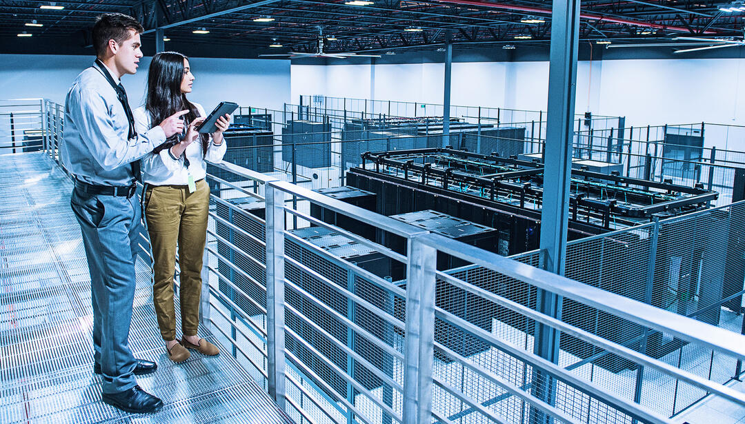 Man and women standing on catwalk above data center