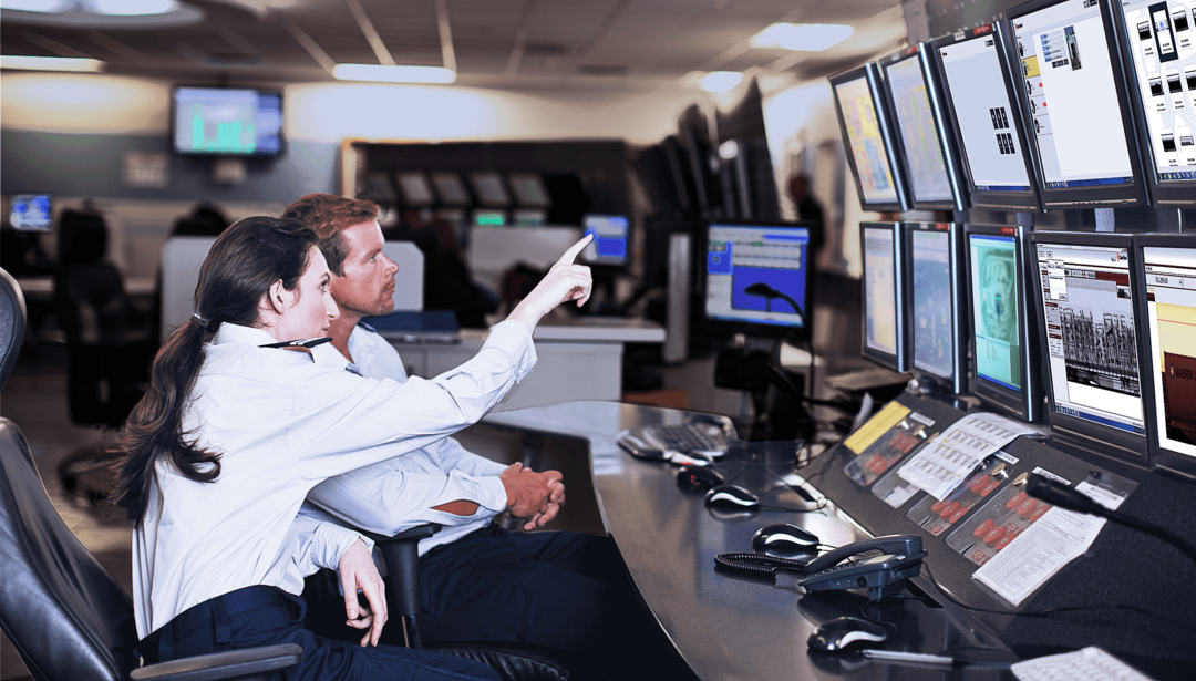 man and woman sitting at multiple screens reviewing information