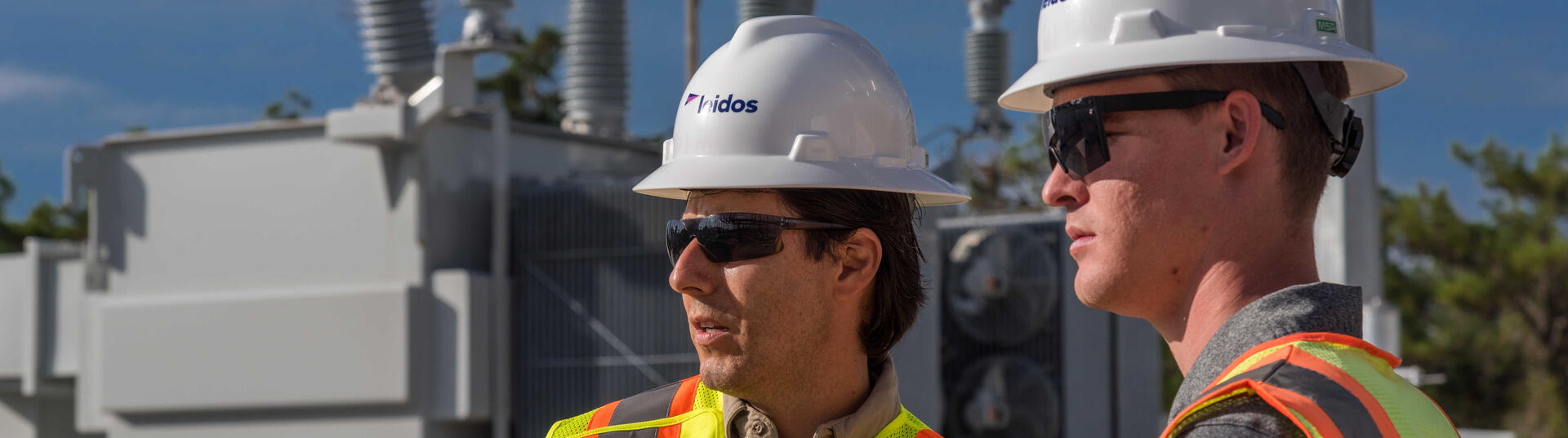 Leidos engineers with hard hats and safety vests at a substation
