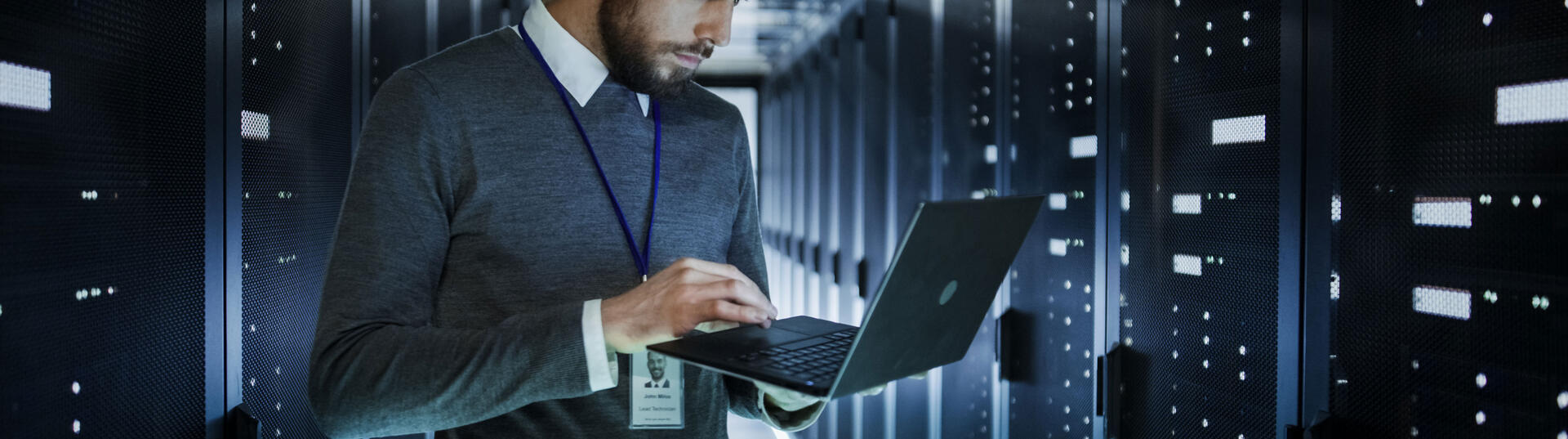 man working on laptop in a data center