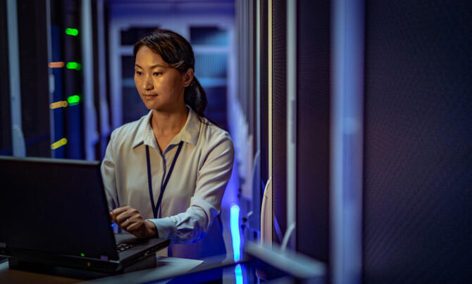 Woman in data center working on a laptop.
