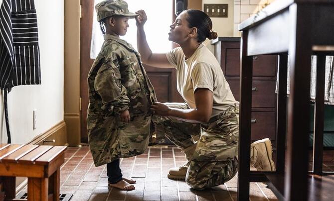 Daughter wearing U.S. soldier mother's uniform at home