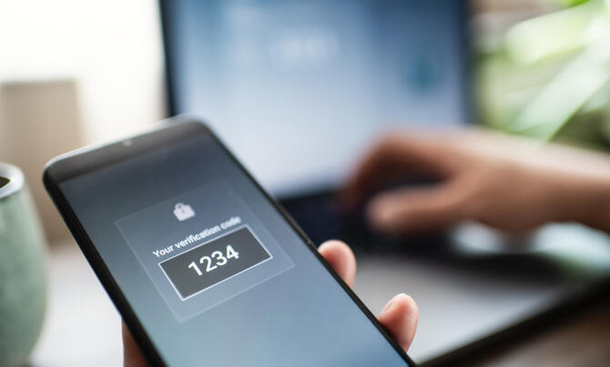 A person with a smartphone and a laptop trying to sign in to a secure system
