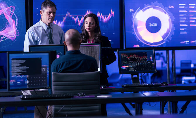 team working with large monitors behind them