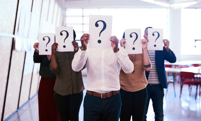 group of people with signs with question marks covering their faces