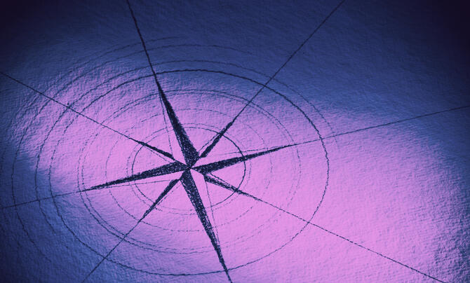 A stylized compass rose is drawn on a textured surface, illuminated by purple and blue lighting. The design features radiating lines and circular markings centered on a star-like shape.