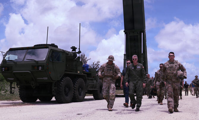 U.S. military personnel and officials walk past a Dark Eagle long-range hypersonic weapon launcher during the Valiant Shield exercise, with the mobile launcher and support vehicle positioned beside the roadway.