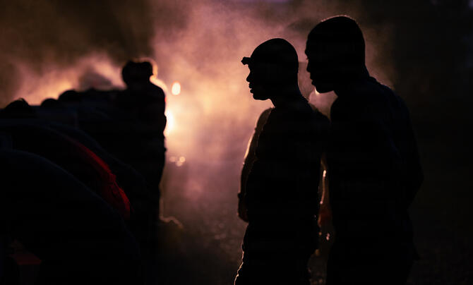 Dark image with silhouettes of US Army ROTC cadets with the backlight obscured by fog