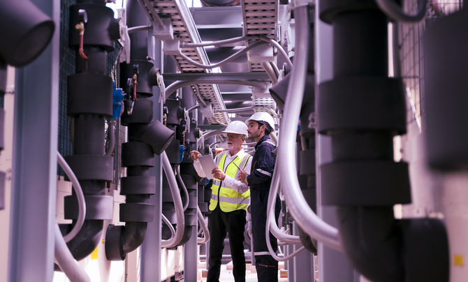 Two engineers working on industrial system on roof