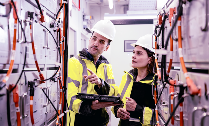 Two engineers monitor an industrial facility energy usage