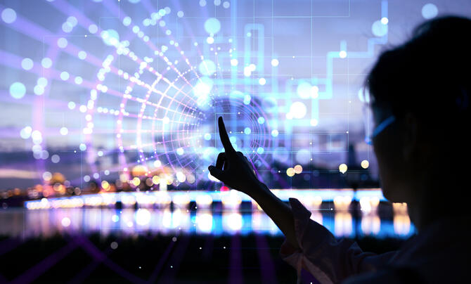 Woman in silhouette touching a transparent screen with city lights in the background