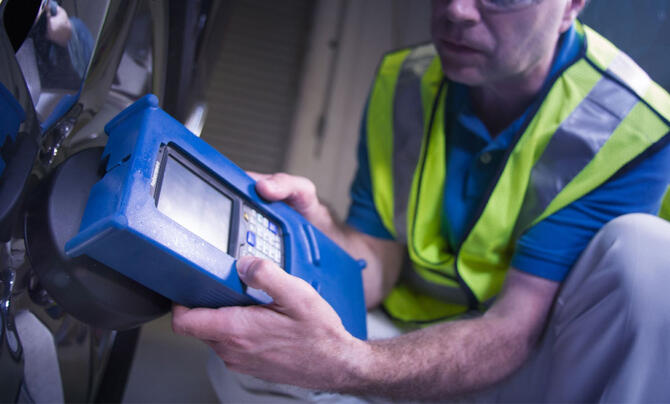 Technician using tire pressure sensor system on vehicle