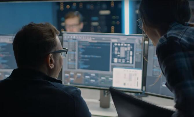 two software developers analyzing their code on a monitor