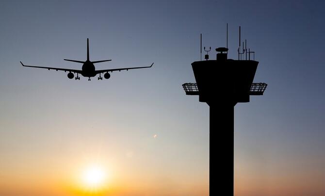 airplane flies by an air traffic control tower