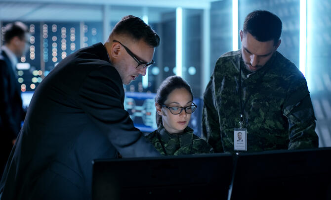 Military and intelligence personnel looking at computer
