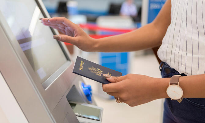 Woman standing at kiosk holding passport