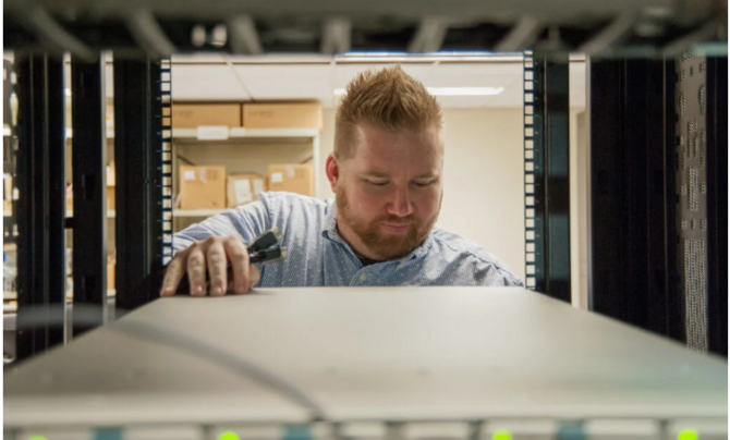 man looking at back of computer with flashlight