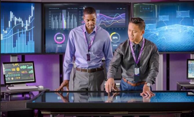 Two men at interactive table discussing analytics