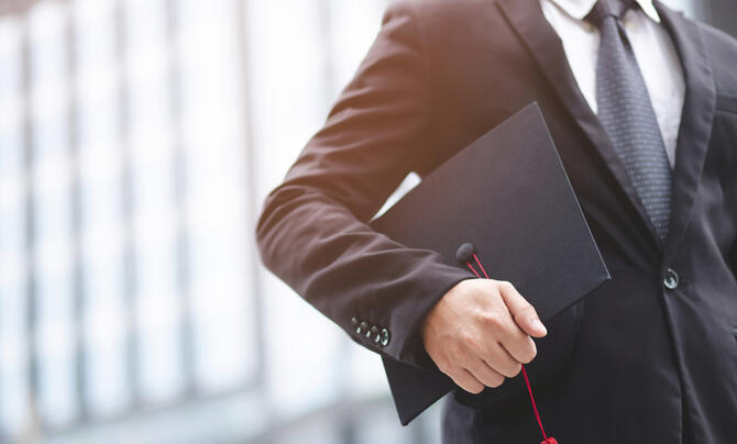 man holding mortarboard by his side