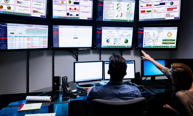 2 people looking at screens and dashboards