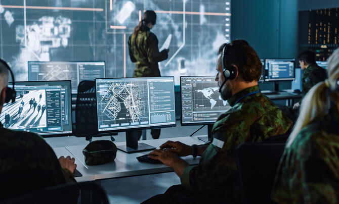 team working with screens showing maps and surveillance footage
