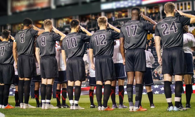 Army Mens Soccer Team lined up on field saluting