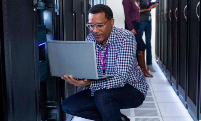 man crouching holding laptop