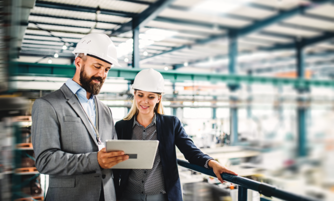 Two people in an industrial environment looking at a tablet
