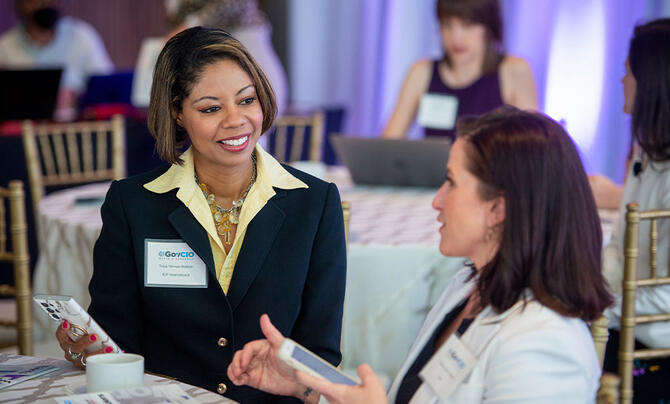 Two women speaking with smartphones in hand