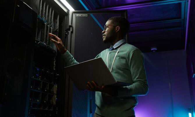 A man working on a large server with a laptop in hand