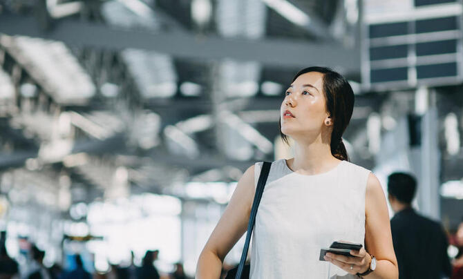 A woman at the airport, looking up at something hanging in the air