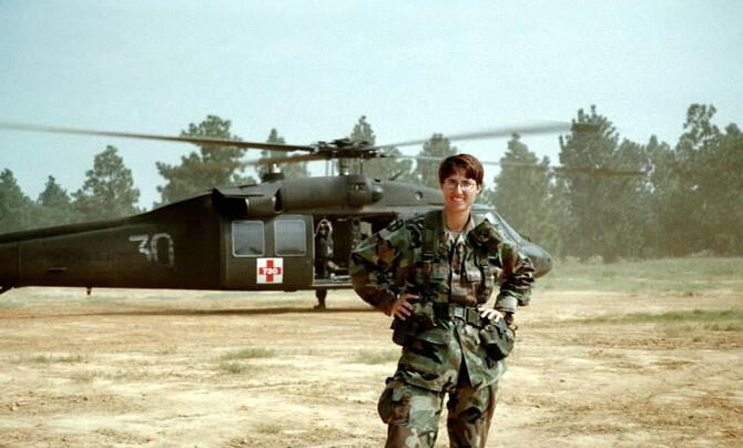 Nanette Patton in the desert with a helicopter behind her