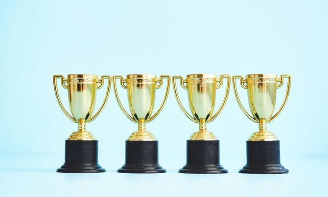 Four trophies in a row with a light green background