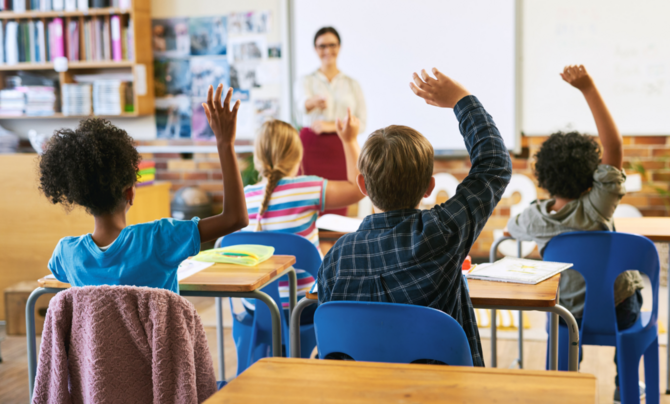 Children in a classroom raising their hands