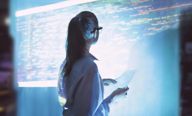 A woman standing in front of a screen with cyber code written on it