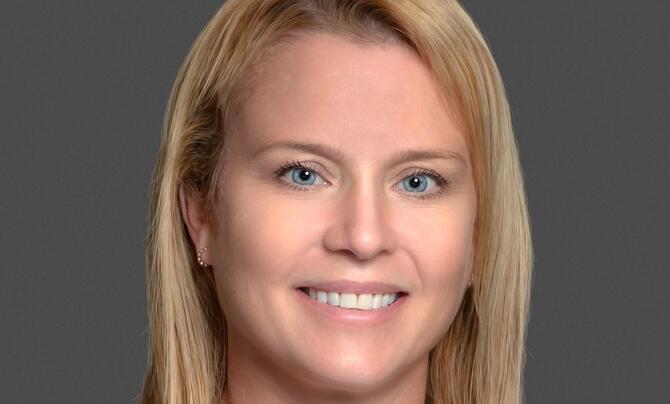 Trisha Eknes headshot in front of a gray background