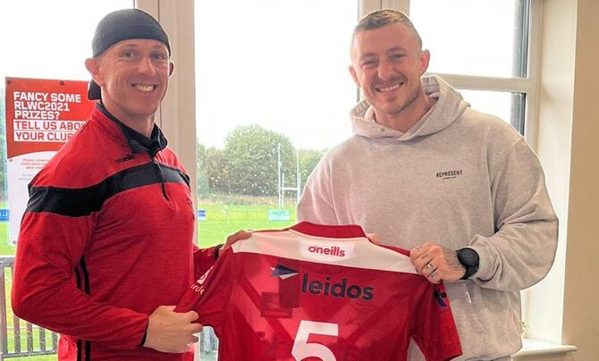 Two men holding up a jersey