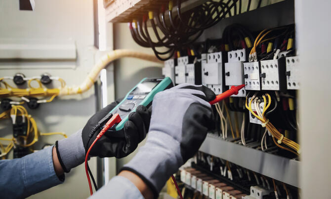 Worker with PPE working on an electrical panel