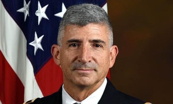 Steve Lewis sitting in front of an American Flag